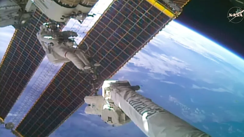NASA astronaut Anil Menon rides the Canadarm2 robotic arm outside the International Space Station to begin installing a roll-out solar array.