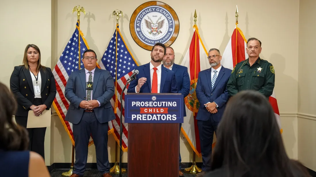 Florida Attorney General James Uthmeier speaks at a podium marked "Prosecuting Child Predators" as Osceola County Sheriff Chris Blackmon and other officials stand behind him, Oct. 28, 2026.