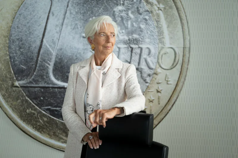 Official European Central Bank photo of ECB President Christine Lagarde standing in front of a large image of a one-euro coin.