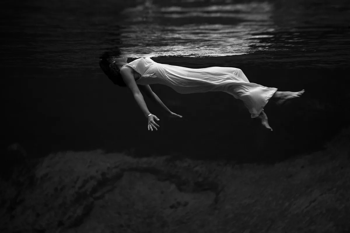 Black-and-white historic photograph of a swimmer in a white dress floating underwater at Weeki Wachee spring