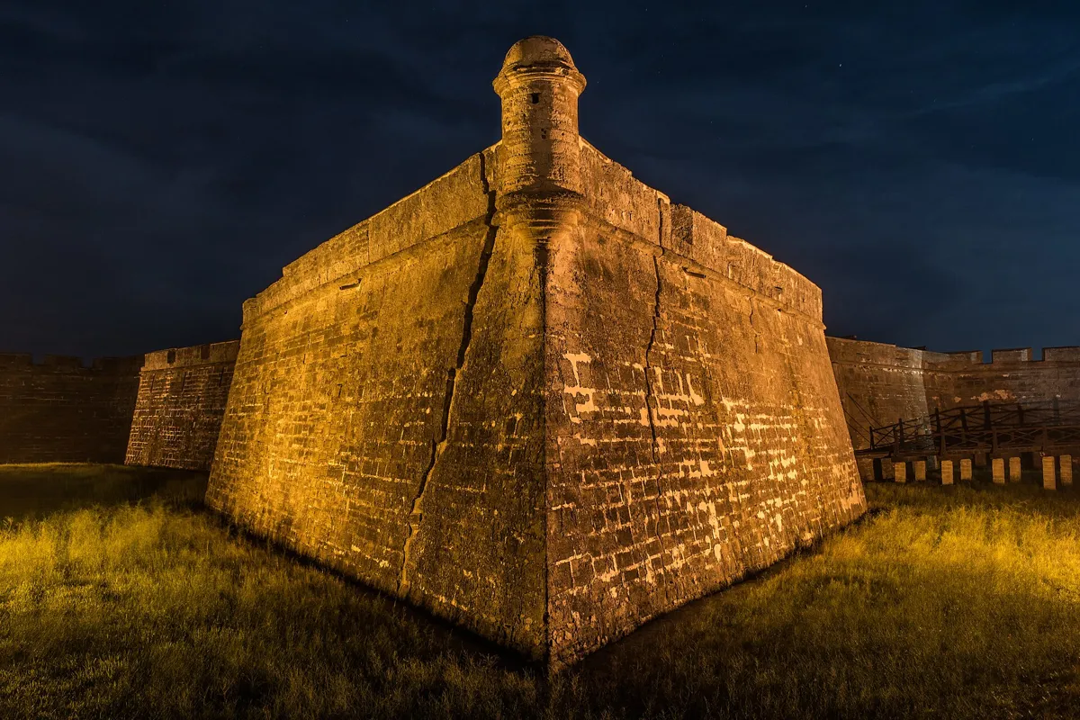 The coquina stone corner bastion of the Castillo de San Marcos lit warmly at night