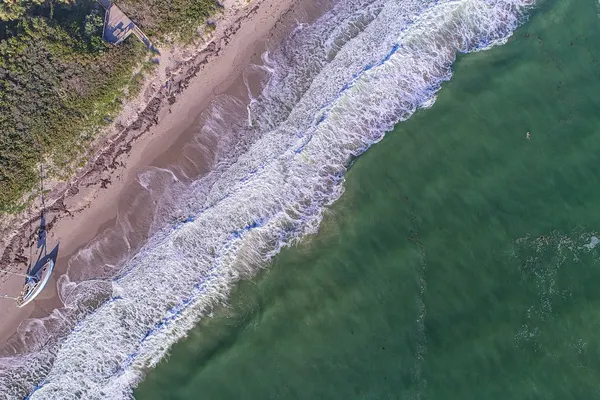 Aerial view of waves breaking on Melbourne Beach beside coastal dune vegetation